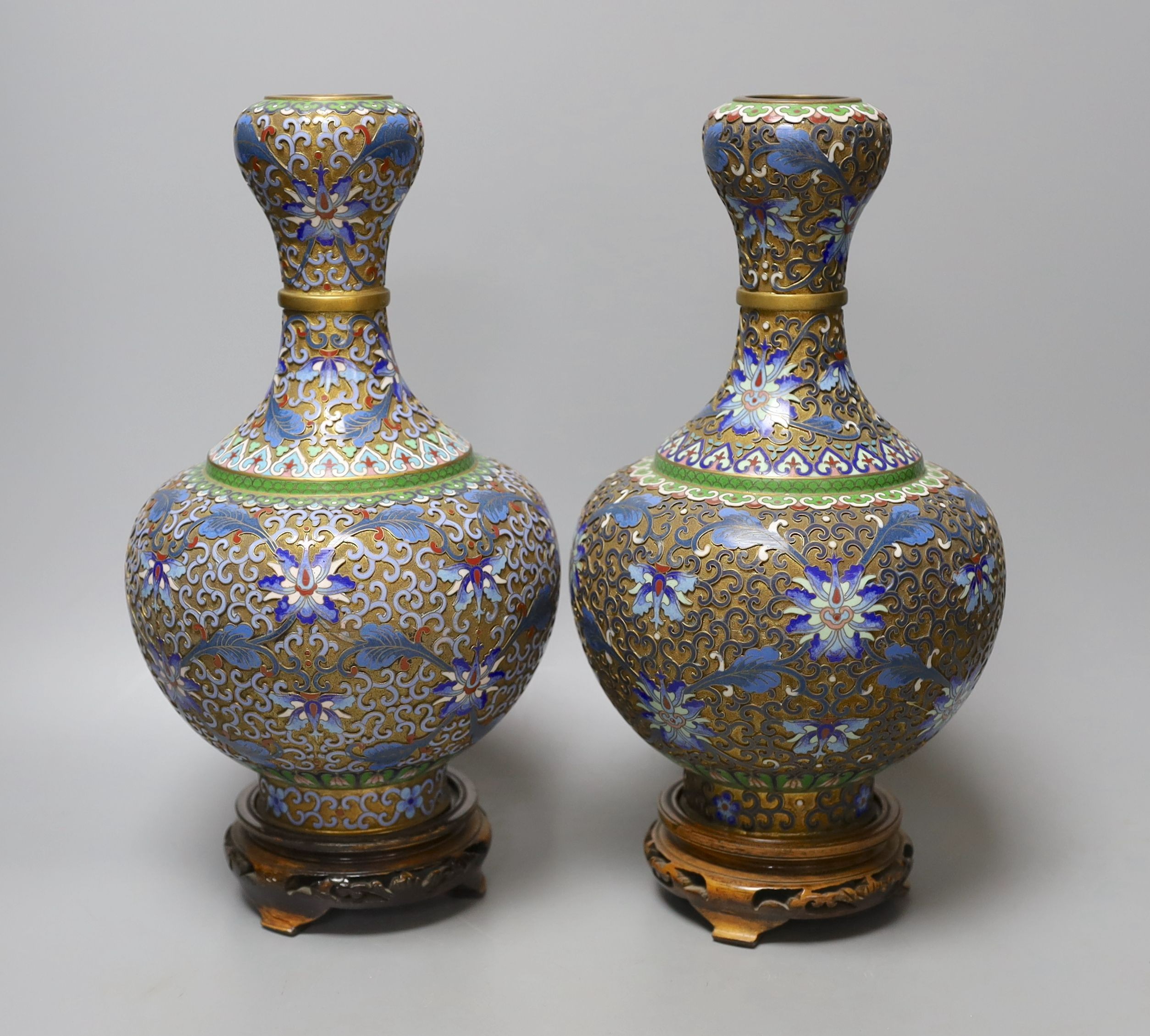 A pair of Chinese cloisonné enamel vases, on carved wood plinths, 30cm